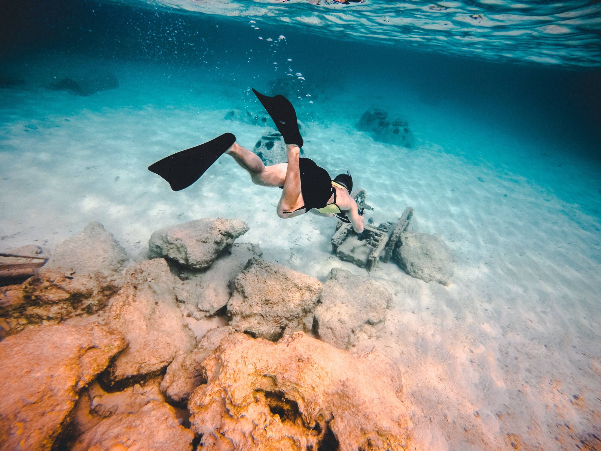 Person scuba diving towards rocks